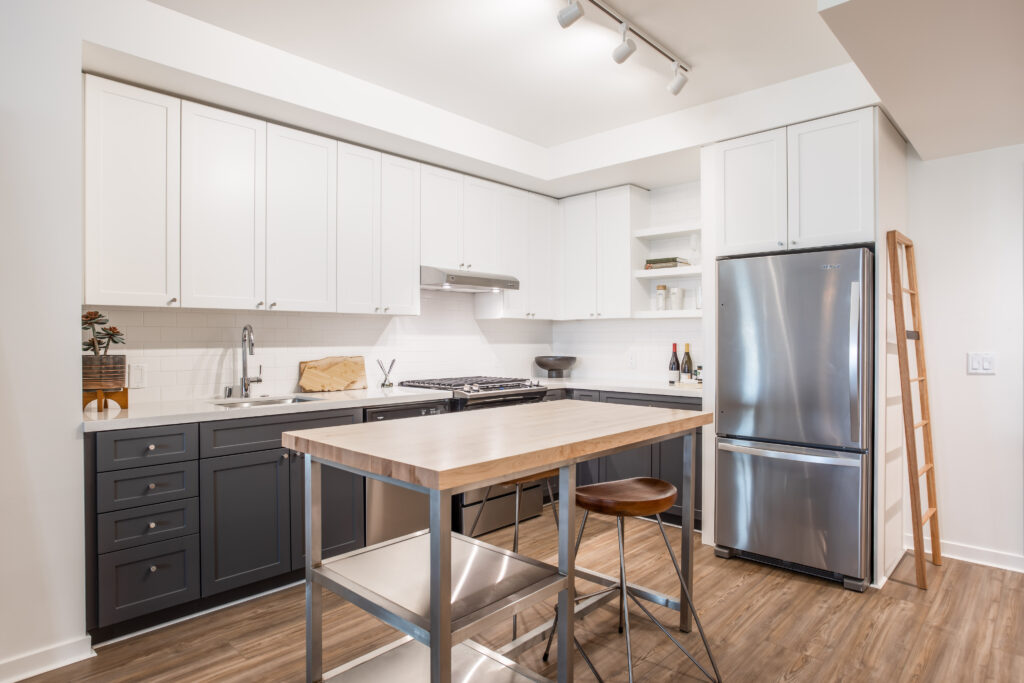Beoautiful kitchen with white upper cabinets, and darker cabinets below, stainless steel appliances